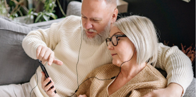 Afbeelding van een stel op de bank met smartphone in de hand en in-ear koptelefoon in de oren.